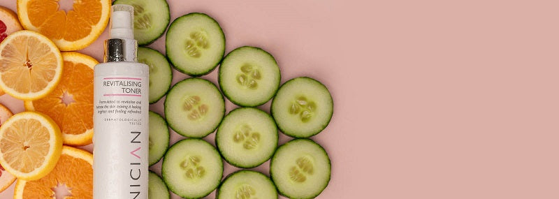 image of SKINICIAN Revitalising Toner laying on cucumbers and oranges