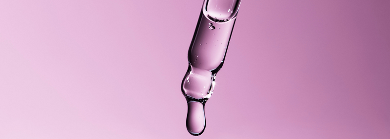 image of pipette with skincare droplet coming from it on purple background