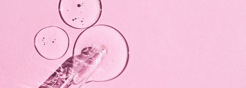 image of pipette dropping liquid onto pink background