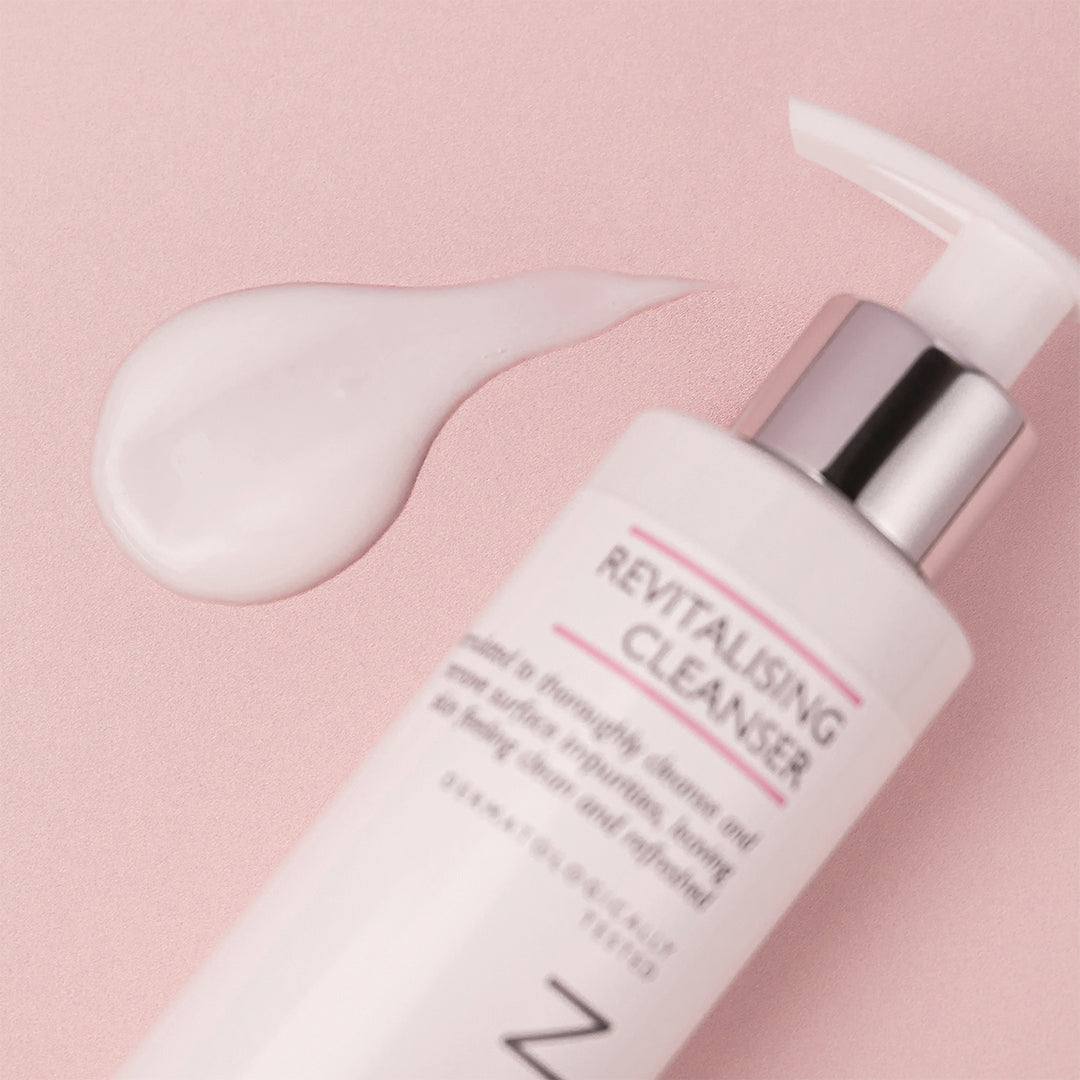 A milky cream texture beside the revitalising cleanser bottle.